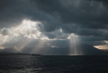 Güneş ışığının manzarası bulutların arasından denizi aydınlatıyor.