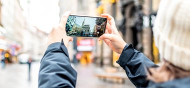 Bir bayan turist akıllı telefonuyla Viyana şehrinin fotoğraflarını çekiyor.