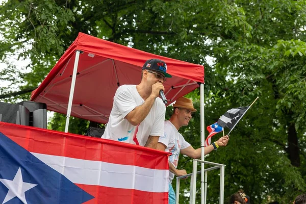 Genç bir adam mikrofonla konuşuyor ve New York 'ta Porto Riko Günü Geçidi' ni kutluyor.