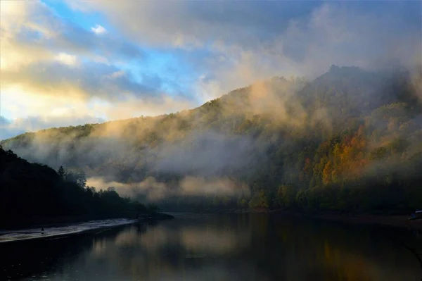 在雾蒙蒙的日子里 湖面与覆盖着秋树的高山相映成趣 — 图库照片