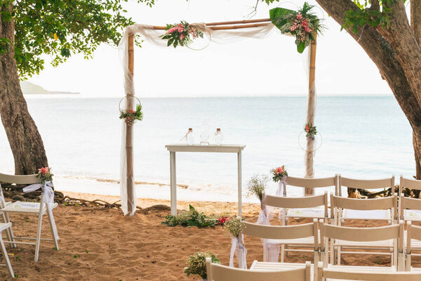 A simple beach wedding set up beside a tree on the seaside