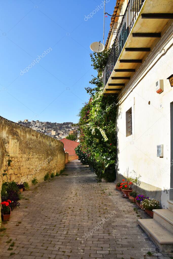 A vertical shot of a narrow alley between old buildings in the old town of Modica
