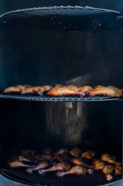 Izgarada pişen tavuk bacaklarının dikey yakın çekimi.