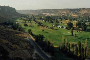 Ağaçlarla dolu bir kanyonda güzel bir golf sahası manzarası.