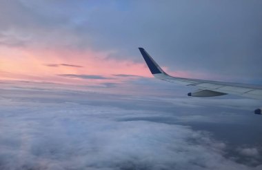 Bulutların üzerinde uçan bir havacı uçağının Kanatlarının Manzarası. Gün batımında hava uçağıyla seyahat etmek..