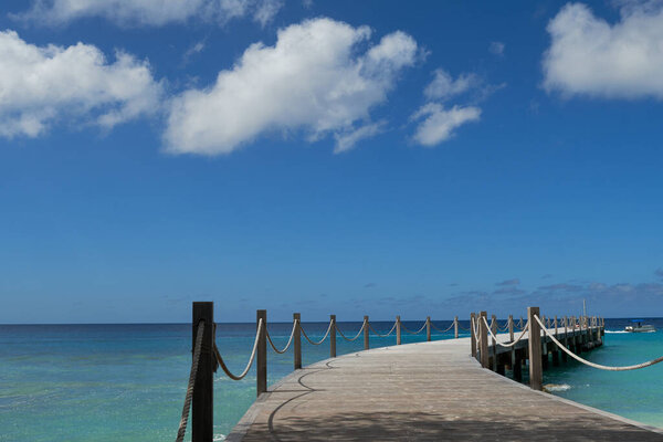 A perspective shot of a wooden walking bridge on the sea.