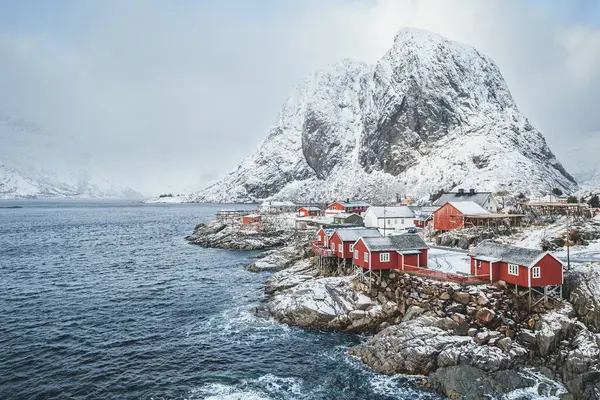 ノルウェー 霧の中の雪の山を背景に ロフトテン島の水の近くの赤い家の風景 — ストック写真