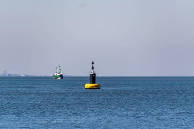 Güneşli bir günde Ostend limanında bir gemi ve sarı bir şamandıra