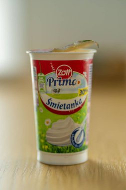 Zott Primo marka krem paketini ahşap bir masada dikey çekiyoruz.