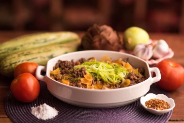 Sebzeler ve farklı malzemelerle çevrili sıcacık bir restoranda servis edilen etli sağlıklı bir yemek.