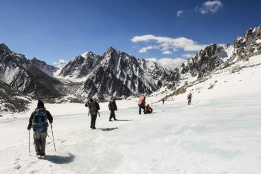 Güneşli bir günde karlı dağlara tırmanan insanların manzarası.