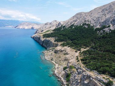 Hırvatistan 'ın Baska kentindeki deniz kıyısında yeşil santralli kayalık uçurumların hava manzarası