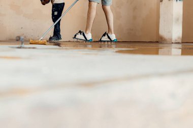 Özel bir aletle zemin astarı uygulayan işçinin yakın plan fotoğrafı.