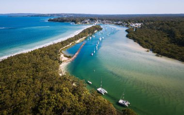 Güneşli bir günde mavi temiz suyu ve tekneleri olan güzel bir okyanusun hava aracı görüntüsü.