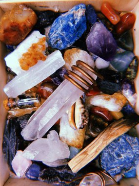 Bir kutu içinde dikey kristal, palo santo ve deniz kabuğu.