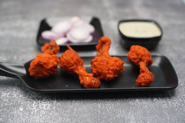 İştah açıcı kızarmış tavuk budu ahşap bir masada sosla servis edilir.