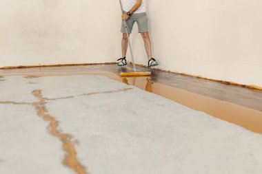 A worker applying yellow epoxy resin to the new floor clipart