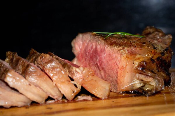 The close-up of delicious sirloin or rump steak grilled on a wooden board