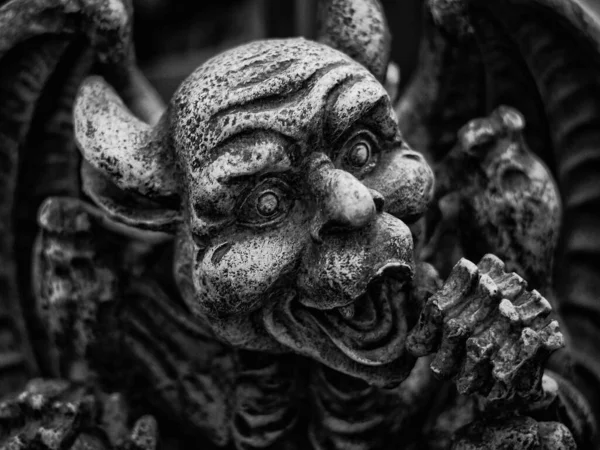 A grayscale closeup of gargoyle statue face