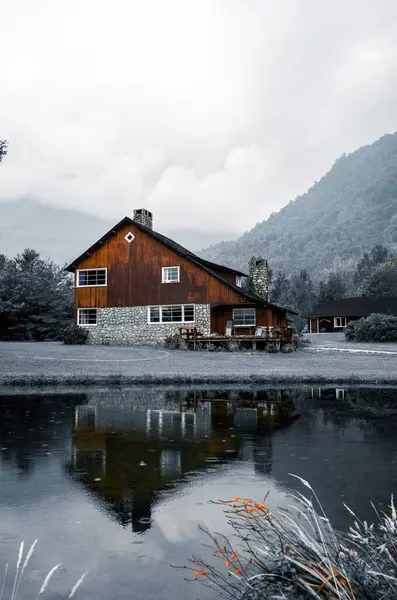背景中湖水和多雾的群山映衬下的一座乡村树屋的立面照片 — 图库照片