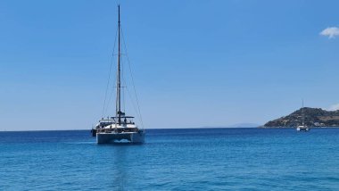 Mavi, berrak gökyüzünün altında okyanusta yelken açan tekneler.