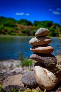 Nehir kenarındaki Zen taşlarının dikey çekimi.