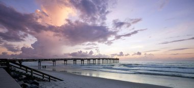 Büyüleyici bir günbatımında, su üzerinde bir iskelenin manzarası.