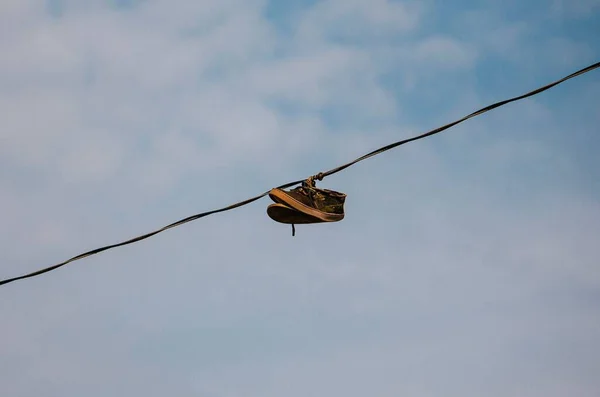 Par Sapatos Velhos Pendurados Fio Elétrico Contra Céu Nublado — Fotografia de Stock