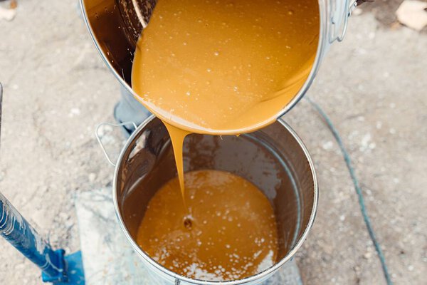 A process of pouring yellow resin from the metal bucket for preparing the floor