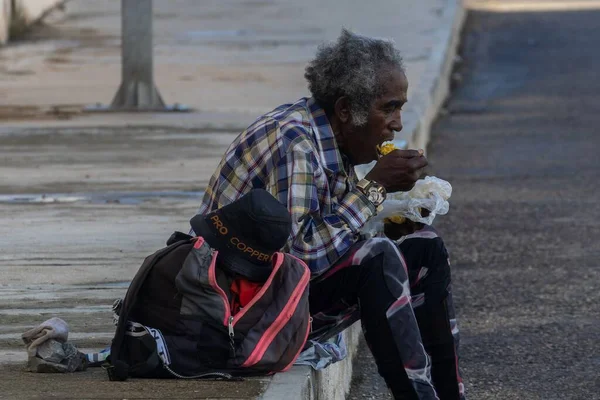 歩道に座ってストリートフードを食べている老人 — ストック写真