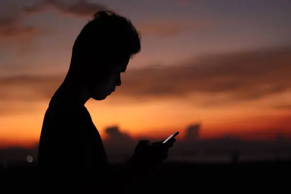 夕日を背景に携帯電話を持っている男のシルエット — ストック写真