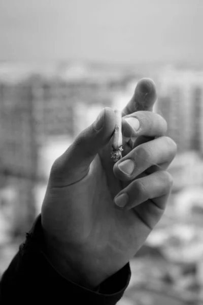 Graustufenaufnahme Einer Zigarette Der Hand Eines Menschen Auf Verschwommenem Hintergrund — Stockfoto