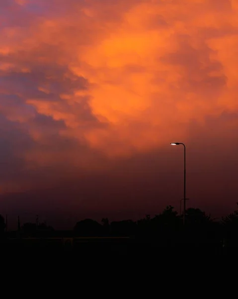 通りの光柱と夕日の間に雲と明るい赤い空 — ストック写真