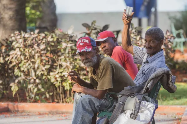 キューバのマタンザスでカップを片手に屋外のベンチで煙草を吸って応援している男たちが — ストック写真