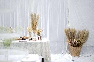 Kurumuş buğday ve sepetin içinde çiçekler ve masanın üstünde saksılar olan güzel bir dekorasyon.