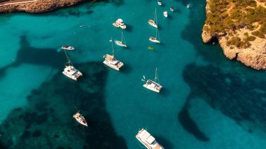 Sakin bir suda yüzen teknelerin manzaralı kuş bakışı görüntüsü.