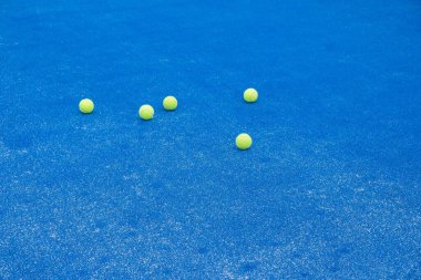 Seçici odaklanma. Sentetik çimenli mavi raket tenis kortu ve birkaç sarı top.