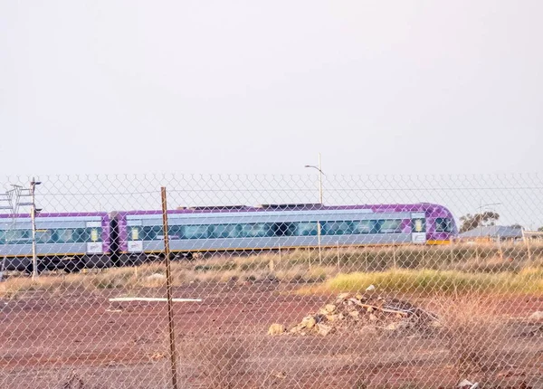 一辆紫色移动的火车穿过金属网 — 图库照片