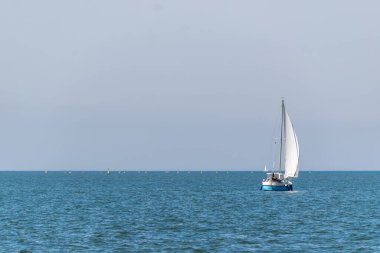 Mavi gökyüzüne karşı denizde güzel bir yelkenli manzarası.