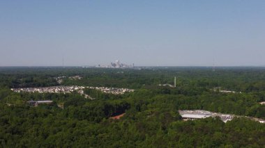 Ağaçlı bir manzara ve arka planda bir şehir.