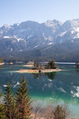 Güneşli bir günde Almanya 'nın Garmisch-Partenkirchen kentinde Wetterstein yakınlarında turkuaz rengi ve küçük adasıyla Eibsee Gölü