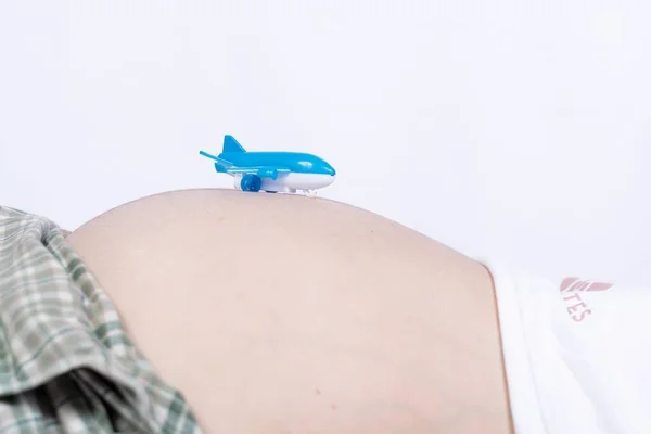 白い背景を持つ妊娠中の腹に青いおもちゃの飛行機の閉鎖 — ストック写真