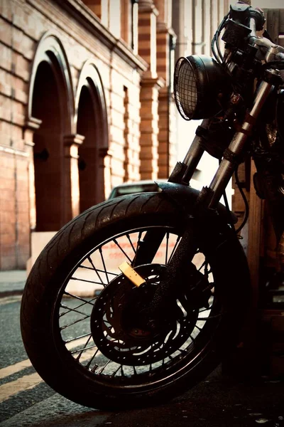 以建筑物为背景的摩托车轮子的垂直镜头 — 图库照片