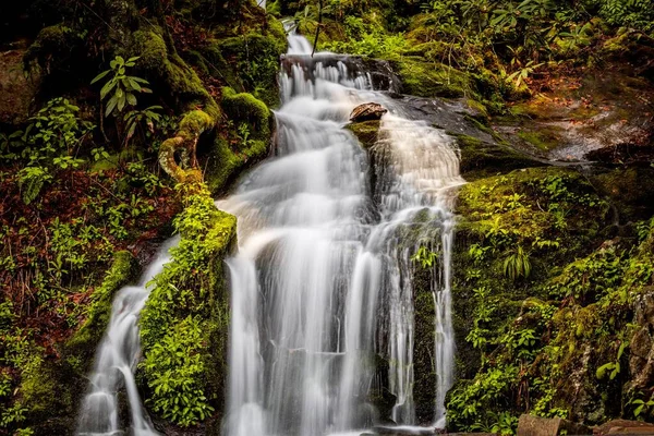 Una Pequeña Cascada Que Fluye Sobre Las Rocas —  Fotos de Stock