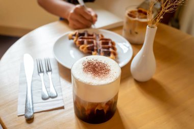 Bir kafede sabah yemeği: bir fincan kahve, bal latte ve Eispanner americano ile waffle.