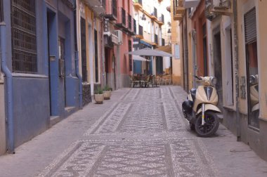 İspanya, Granada 'da dar bir sokakta duvarın yanına park etmiş bir scooter.