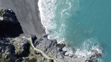Gündüz vakti kayalara çarpan okyanus dalgalarının hava görüntüsü.