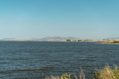 Arkasında dağ sıraları olan büyük bir gölün çarpıcı manzarası.