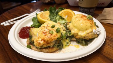 Benedict yumurtalı, limonlu ve yeşillikli bir yemeğin yakın çekimi.