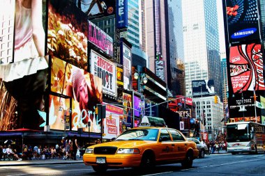 Gündüz vakti New York City, ABD 'de Times Meydanı' nın dijital reklam panolarının önünden geçen sarı bir taksi.